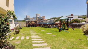 Un patio con un parque infantil, escalones de piedra y vistas a edificios modernos.