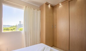 Um quarto com uma cama, uma janela com cortinas e armários de madeira.