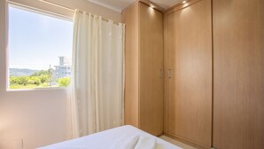 Un dormitorio con cama, ventana con cortinas y armarios de madera.