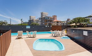 Piscina no terraço com vista para edifícios ao redor.