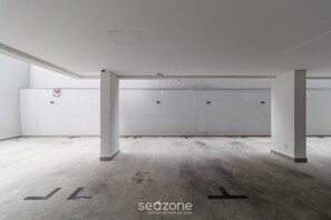 A spacious, empty parking garage with concrete floors and white walls. - Building With Swimming Pool in Ingleses Norte - STN (Florianópolis)