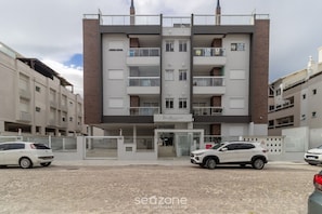 A multi-story building with a restaurant on the ground floor, featuring balconies and a brick facade. - Building With Swimming Pool in Ingleses Norte - STN (Florianópolis)