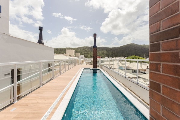 A rooftop pool with a clear view of the surrounding buildings and a distant mountain. - Building With Swimming Pool in Ingleses Norte - STN (Florianópolis)