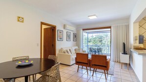 A dining area with a table and chairs, a sofa, and a balcony with a view. - Charm and Comfort 450m From the Beach! Cmh0202 (Florianópolis)