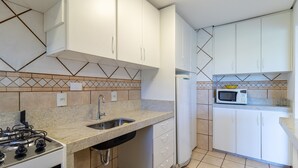 A kitchen with white cabinets, a granite countertop, a stainless steel sink, a gas stove, and a microwave.