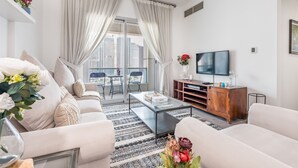 Un salon moderne avec un canapé, une table basse et un téléviseur. Il y a un balcon avec vue sur les immebles.