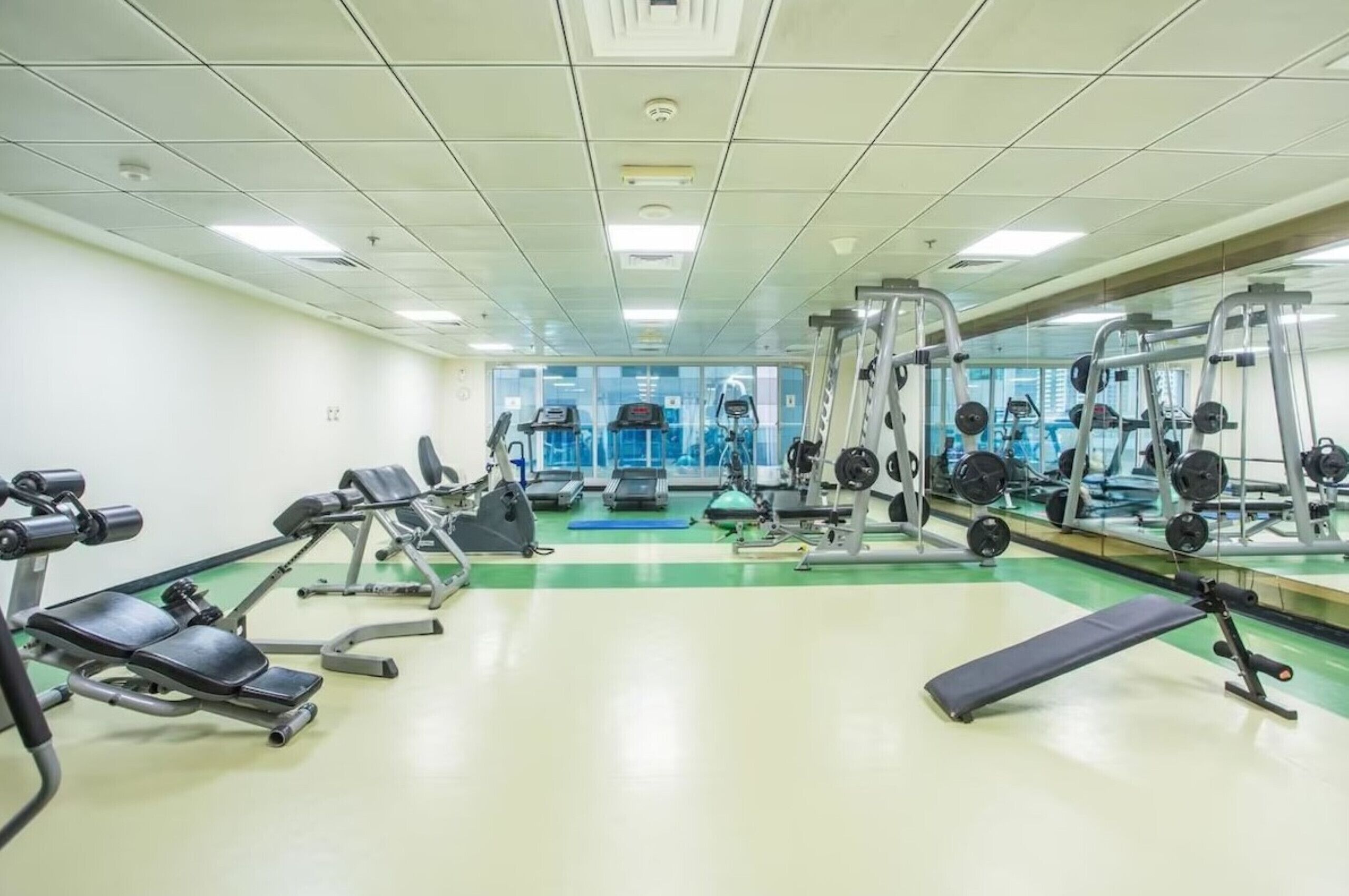 A gym with various exercise equipment, including treadmills, weight machines, and free weights.