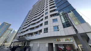 Un immeuble moderne de grande hauteur, doté d’une façade en verre et de nombreux balcons.