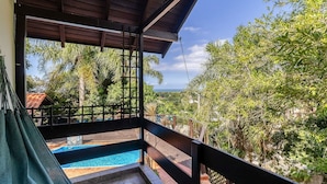 Un balcón con vista a una piscina y exuberante follaje.