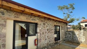 A stone building with a wooden roof, a fire extinguisher, and a paved entrance. - Casa Küçükköy (Ayvalik)