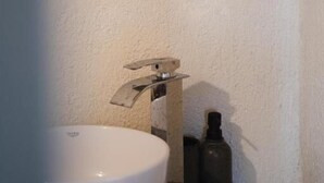 A bathroom with a white sink, a round mirror, and a wooden countertop. - Casa Küçükköy (Ayvalik)