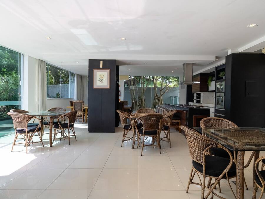 A spacious indoor area with wicker furniture, a glass table, and a kitchen area visible through glass doors.