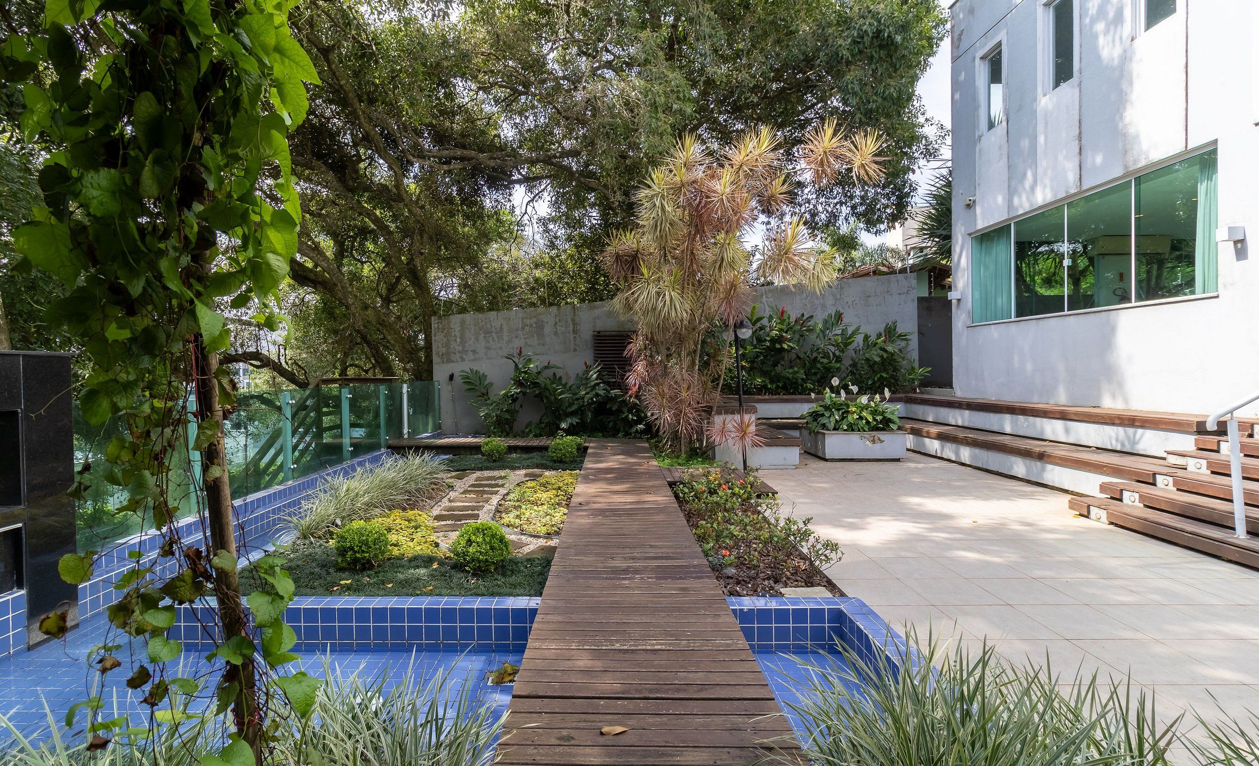 Un sendero de madera que conduce a un edificio moderno con un jardín cubierto de azulejos azules.