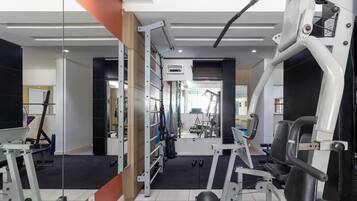 A gym with exercise equipment, mirrors, and a black rubber floor.