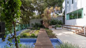 A wooden pathway leading to a modern building with a blue-tiled garden area.