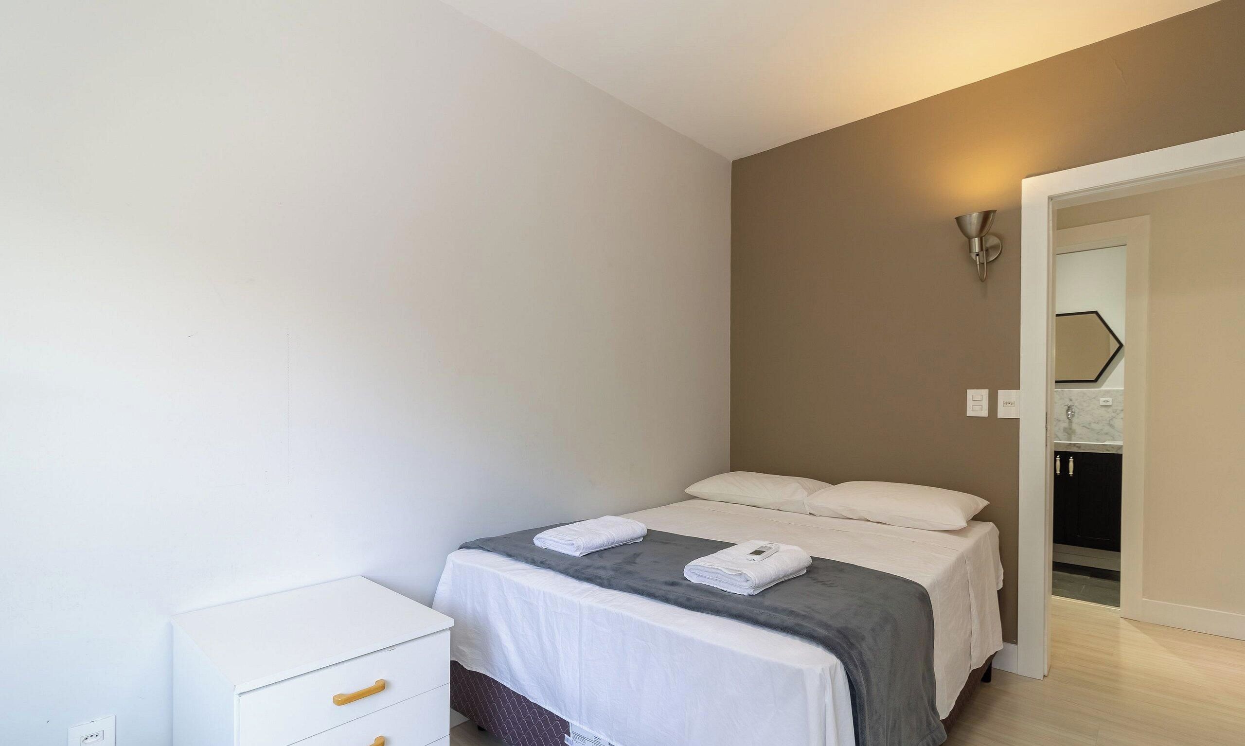 Una habitación de hotel con cama, mesita de noche y armario.