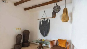 A room with a wooden chair, a glass table with fruits, and two decorative vases. - Lovely 1BR Penthouse, Private pool, fast wifi (Playa del Carmen)
