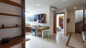 A modern kitchen with wooden cabinets, a gas stove, and a microwave. There is a dining area with a table and chairs. - Lovely 1BR Penthouse, Private pool, fast wifi (Playa del Carmen)