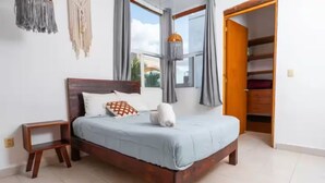 A neatly made bed with a wooden frame, a small bedside table, and a wardrobe with a mirror. - Lovely 1BR Penthouse, Private pool, fast wifi (Playa del Carmen)
