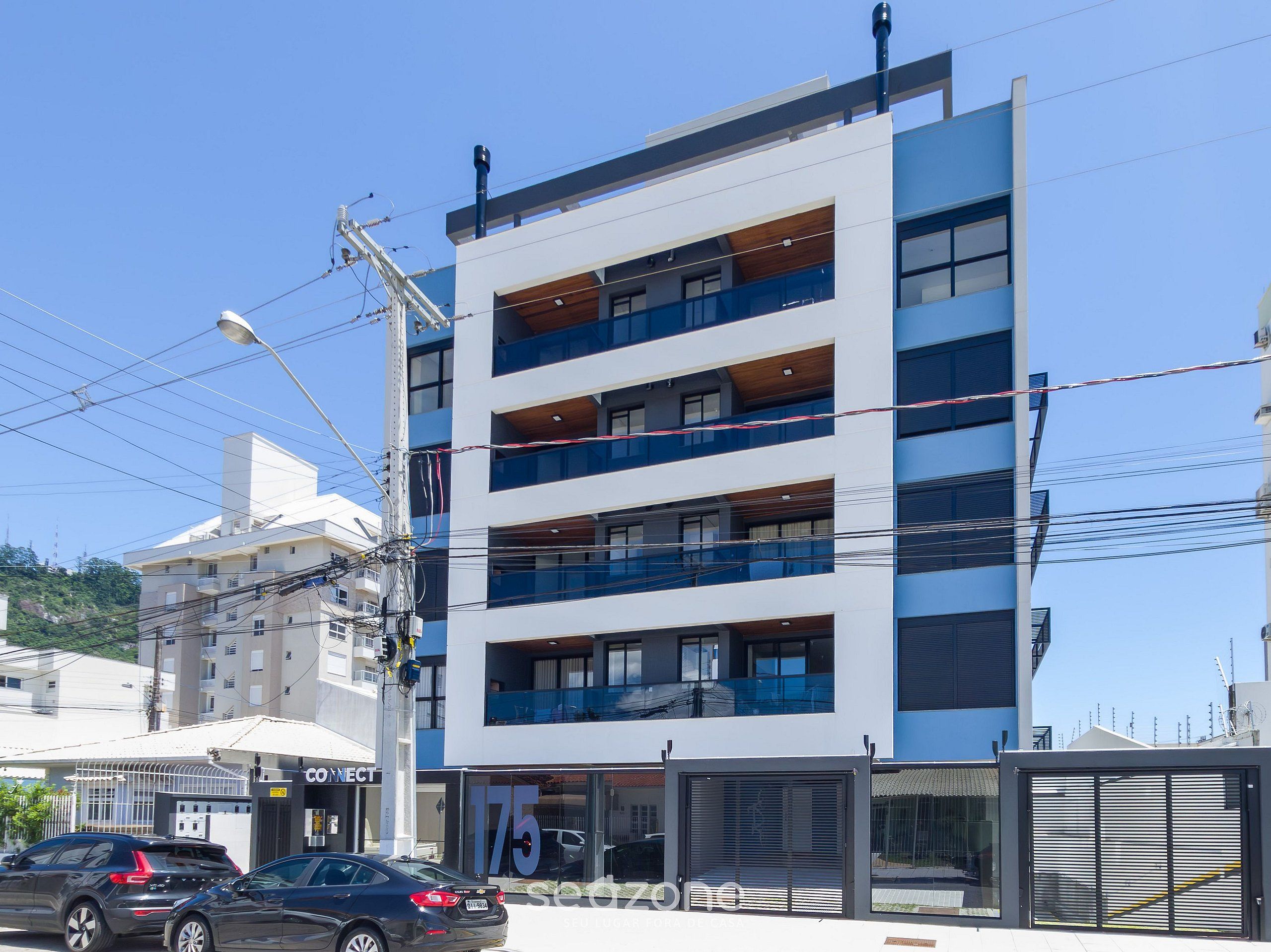 Un edificio de varios pisos con balcones, un escaparate visible y vista a la calle.