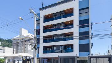 Un edificio de varios pisos con balcones, un escaparate visible y vista a la calle.