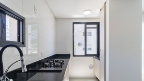 A modern kitchen with a stainless steel sink, black countertop, and a gas stove. - Modern Studio 650m From Ufsc - Cnt303 (Florianópolis)
