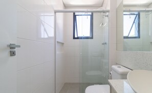 Un baño moderno con ducha de vidrio, inodoro y lavamanos.