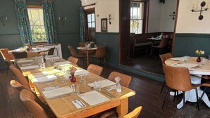 Un restaurante con mesas y sillas de madera, menús y vasos.
