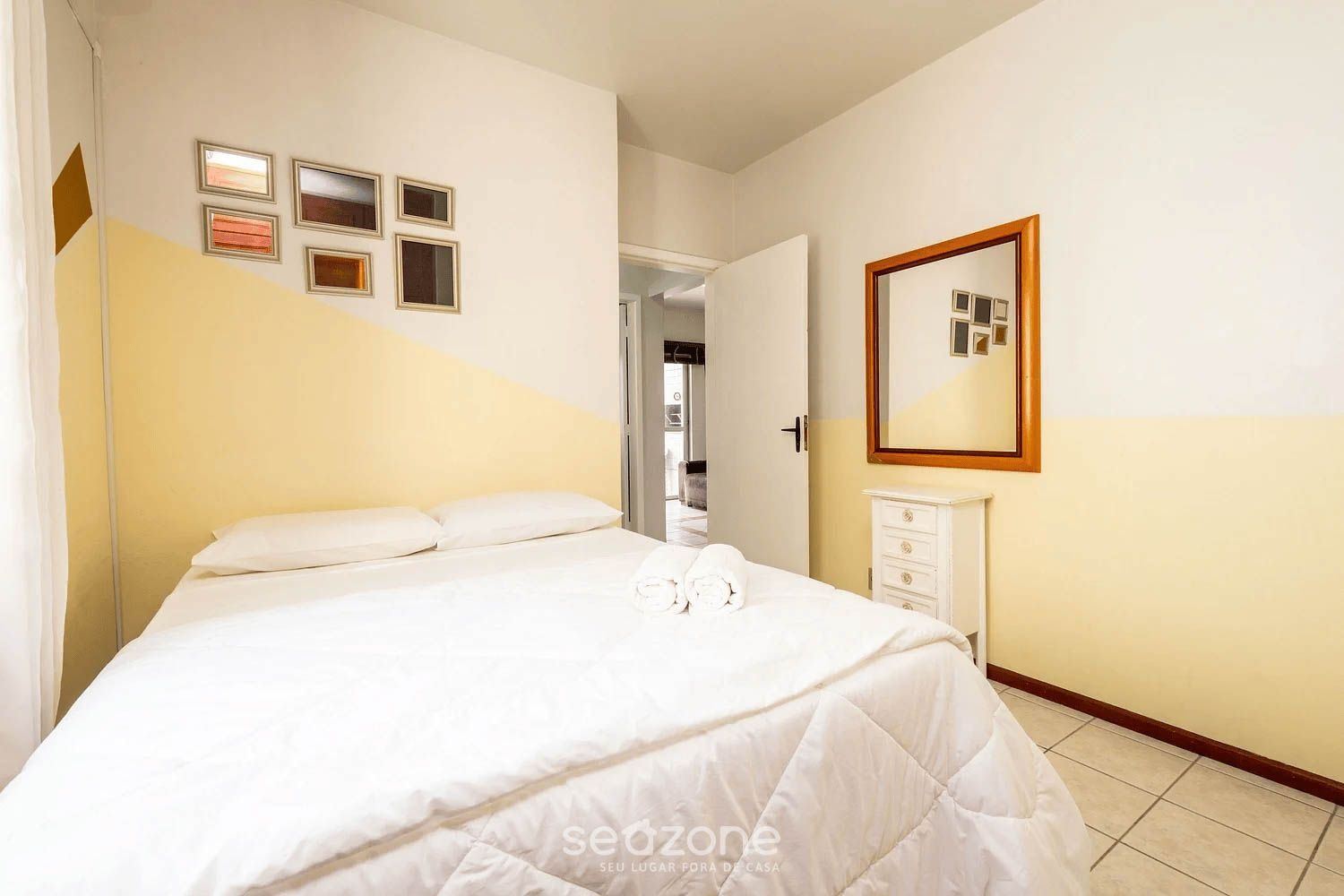 Hotellihuone, jossa on sänky, lipasto ja peili.