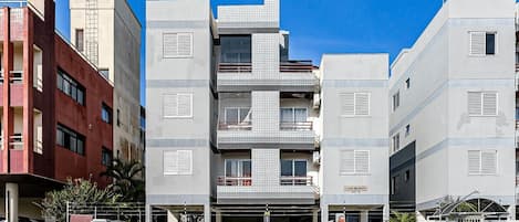 Ένα πολυώροφο κτίριο κατοικιών με μπαλκόνια, μια πύλη στην είσοδο και έναν καθαρό ουρανό.