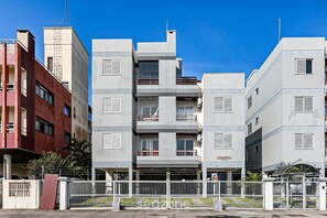 Un immeuble résidentiel à plusieurs étages, doté de balcons, d’une entrée sécurisée et surplombant un ciel dégagé.