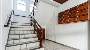 A staircase with wooden handrails and a tiled floor, leading to a room with a wall-mounted storage unit.