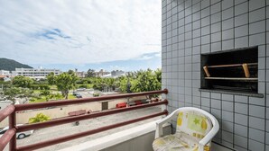 A balcony with a view of a parking lot and buildings, a tiled wall, and a small window.