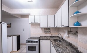 Une cuisine avec des meubles blancs, une cuisinière et un évier.