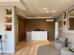 A reception area with a marble counter, wooden panel walls, and a tiled floor.