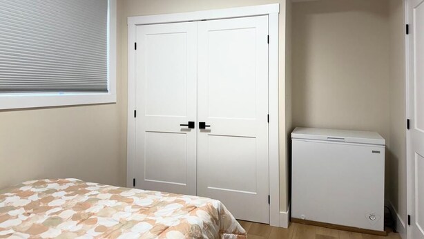 Een slaapkamer met een bed, een kledingkast en een klein wit apparaat, waarschijnlijk een minibar.