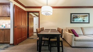 A dining area with a table and chairs, a sofa, a hanging light fixture, and a framed picture on the wall. - Resort at Squaw Creek Tahoe Hyatt 2Bd/2Ba Fireplace Suite (Olympic Valley)