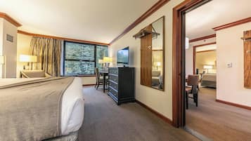 Une chambre d’hôtel avec un lit, un bureau équipé d’un ordinateur, une commode et une grande fenêtre.