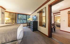 Une chambre d’hôtel avec un lit, un bureau équipé d’un ordinateur, une commode et une grande fenêtre.