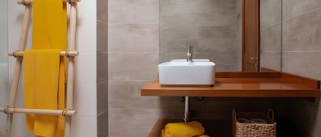 Un baño con un perchero de madera, un lavamanos blanco y una cesta tejida en un estante.