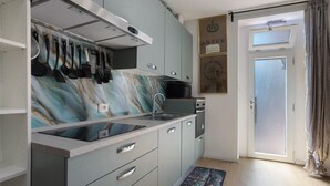 Una cocina con salpicadero de mármol, electrodomésticos de acero inoxidable y una puerta corrediza de vidrio que da a un balcón.
