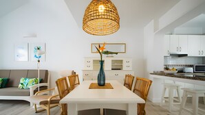 Una cocina moderna con armarios blancos, una mesa de comedor con sillas y una lámpara colgante.