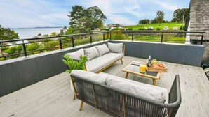 A balcony with a sofa, a small table, and a plant.