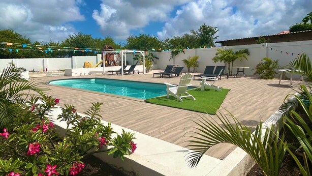 A backyard with a swimming pool, lounge chairs, and a small play area. - 2 persons apartment, Julianadorp (Willemstad)