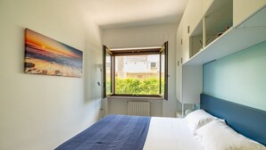 Een slaapkamer met een bed, een raam met uitzicht, een schilderij aan de muur en inbouwkasten.
