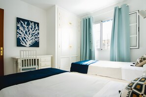 A bedroom with two beds, a white dresser, a white chair, a large window with curtains, and a wall art piece. - Holiday Home 'Caleta Campos Bungalows' with Sea View, Shared Pool and Wi-Fi (Arrieta)