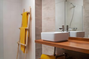 A bathroom with a wooden vanity, a mirror, a shower, and a towel rack with yellow towels. - Holiday Home 'Caleta Campos Bungalows' with Sea View, Shared Pool and Wi-Fi (Arrieta)
