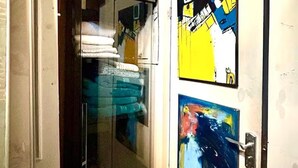 A hotel room with a minibar, a door with artwork, and a red sign above the minibar. - Arty Infused Loft With ac Near Emirates Stadium (London)