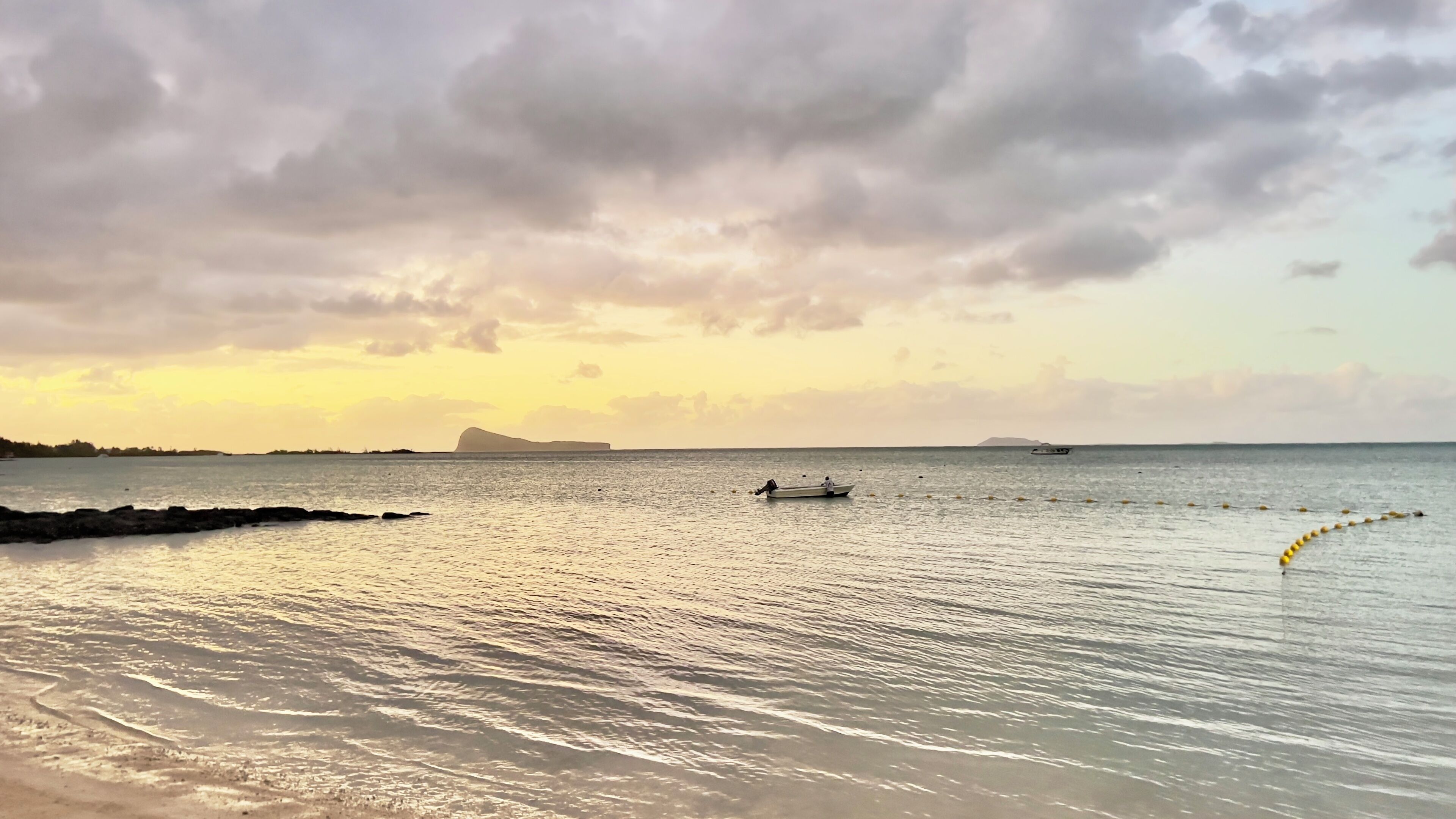 A calm sea with a boat and a distant island.
