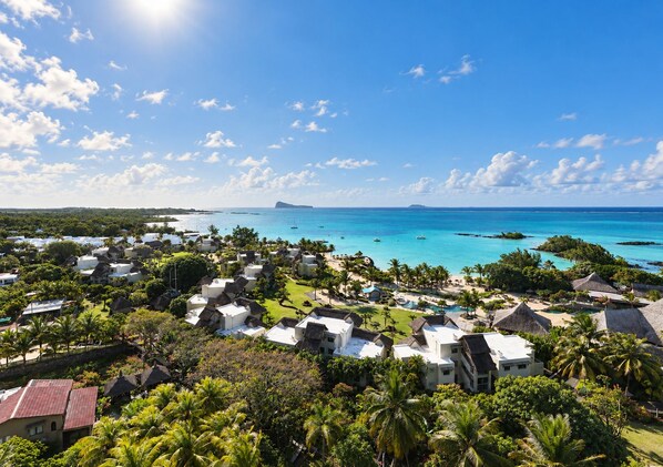 A resort with multiple bungalow-style accommodations, a central pool, and a view of the ocean.